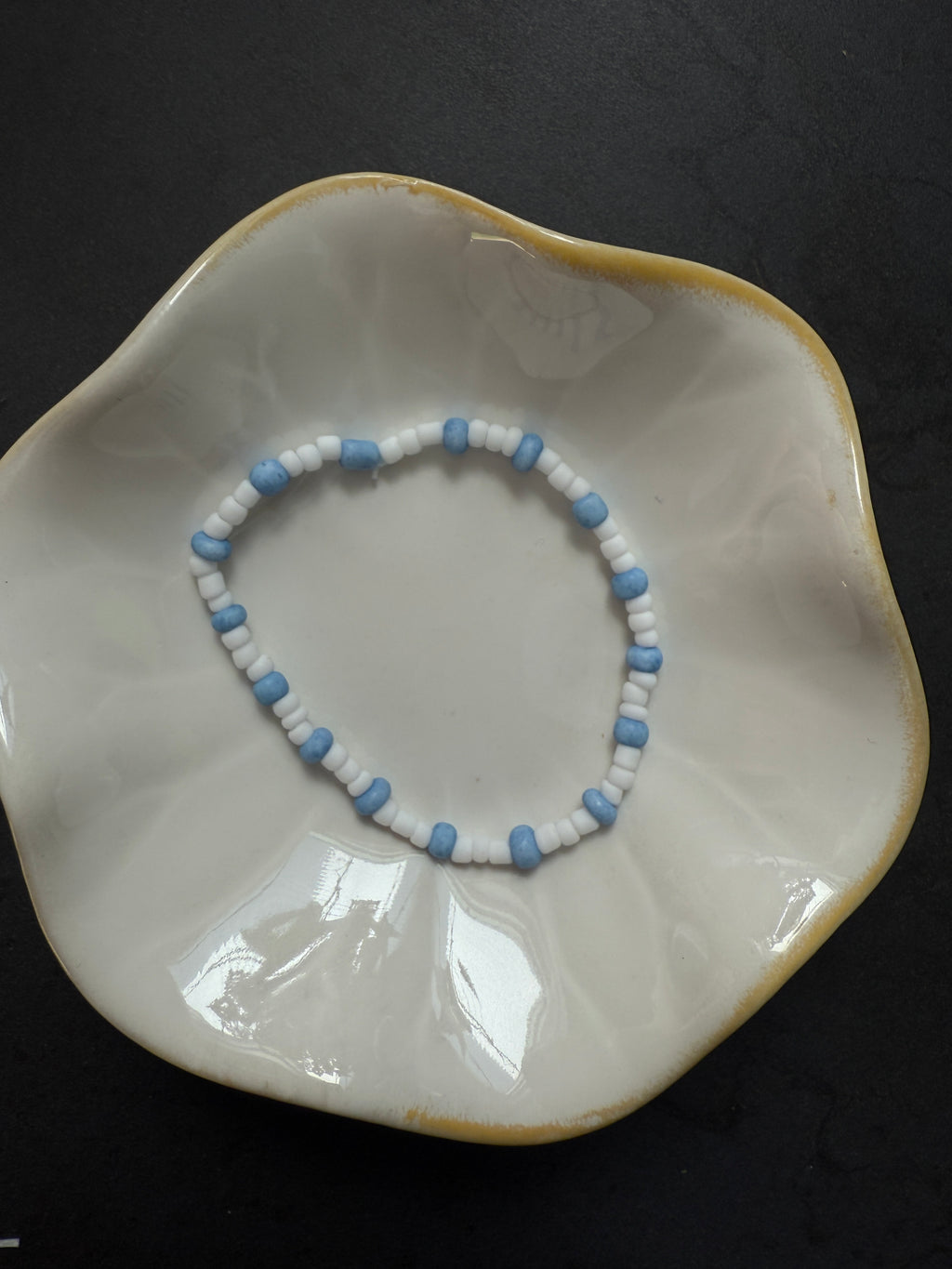 Armand mit weißen Perlen in verschiedenen Farben