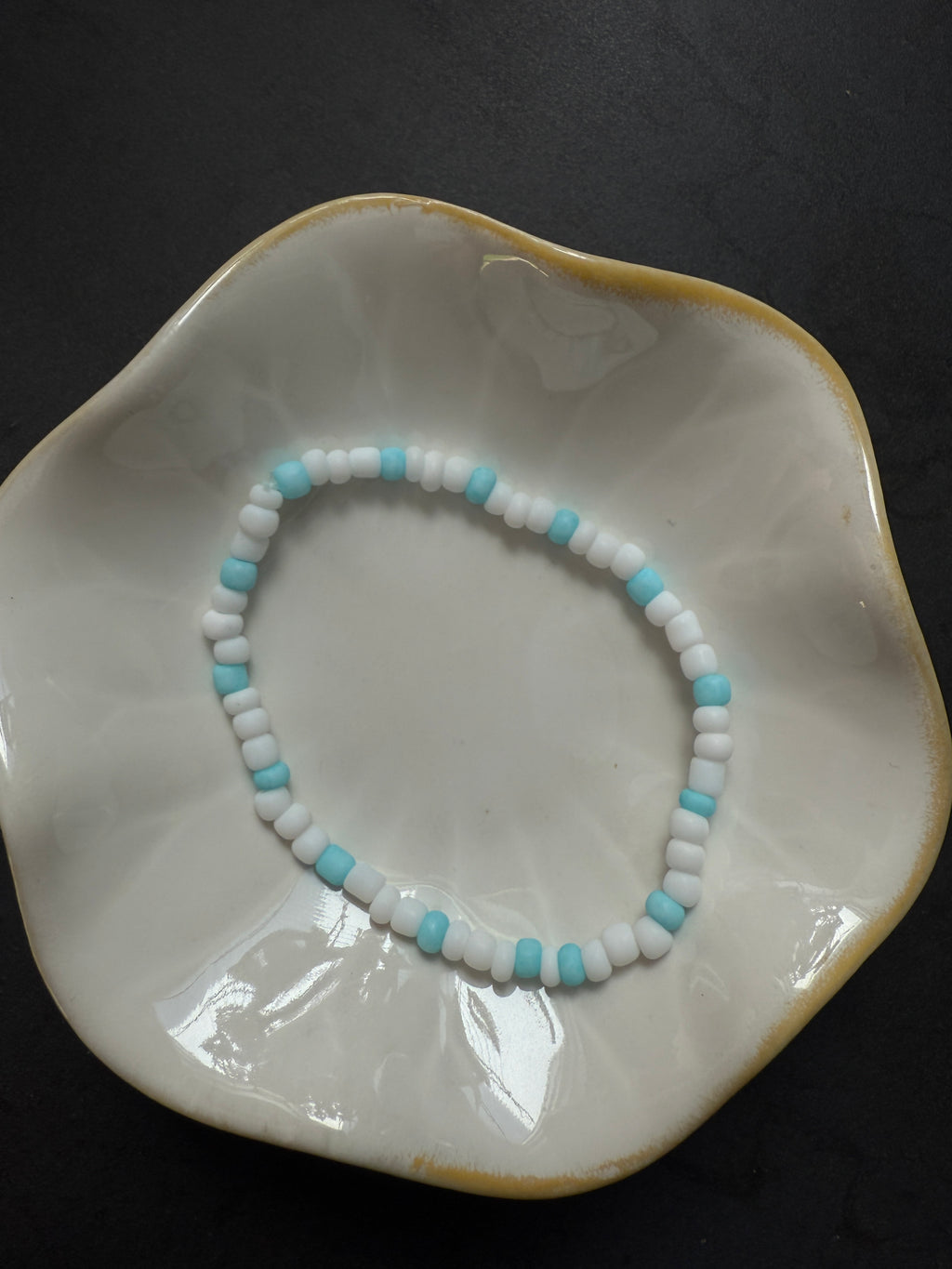 Armand mit weißen Perlen in verschiedenen Farben