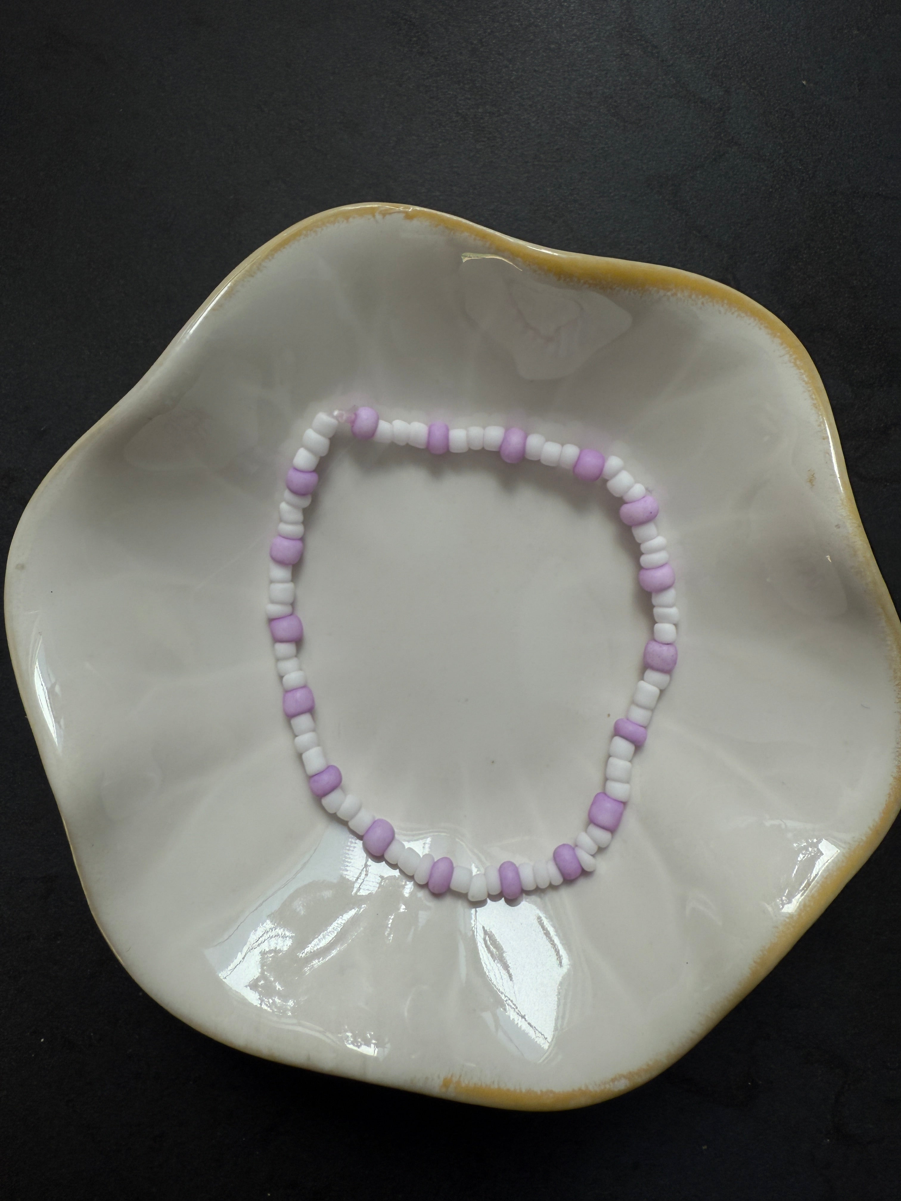 Armand mit weißen Perlen in verschiedenen Farben