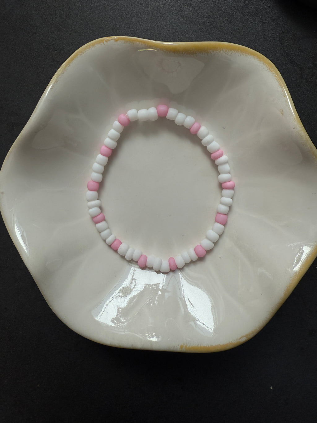 Armand mit weißen Perlen in verschiedenen Farben