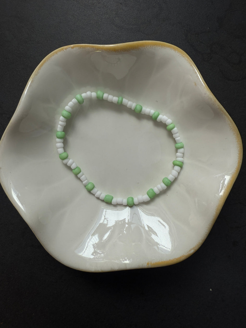 Armand mit weißen Perlen in verschiedenen Farben