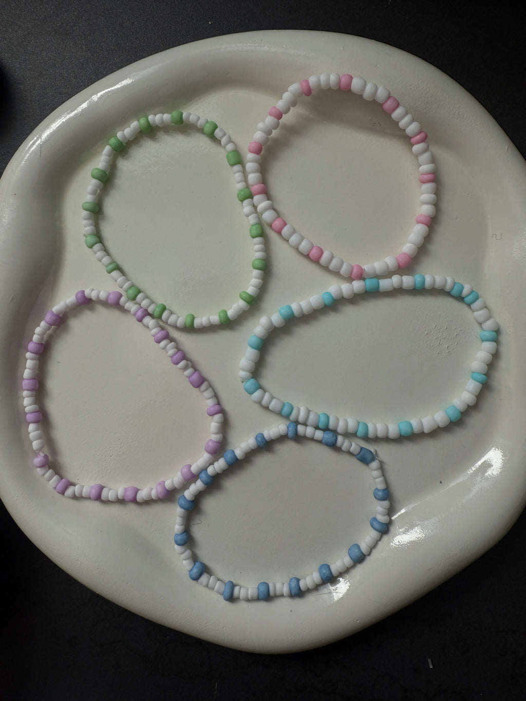 Armand mit weißen Perlen in verschiedenen Farben